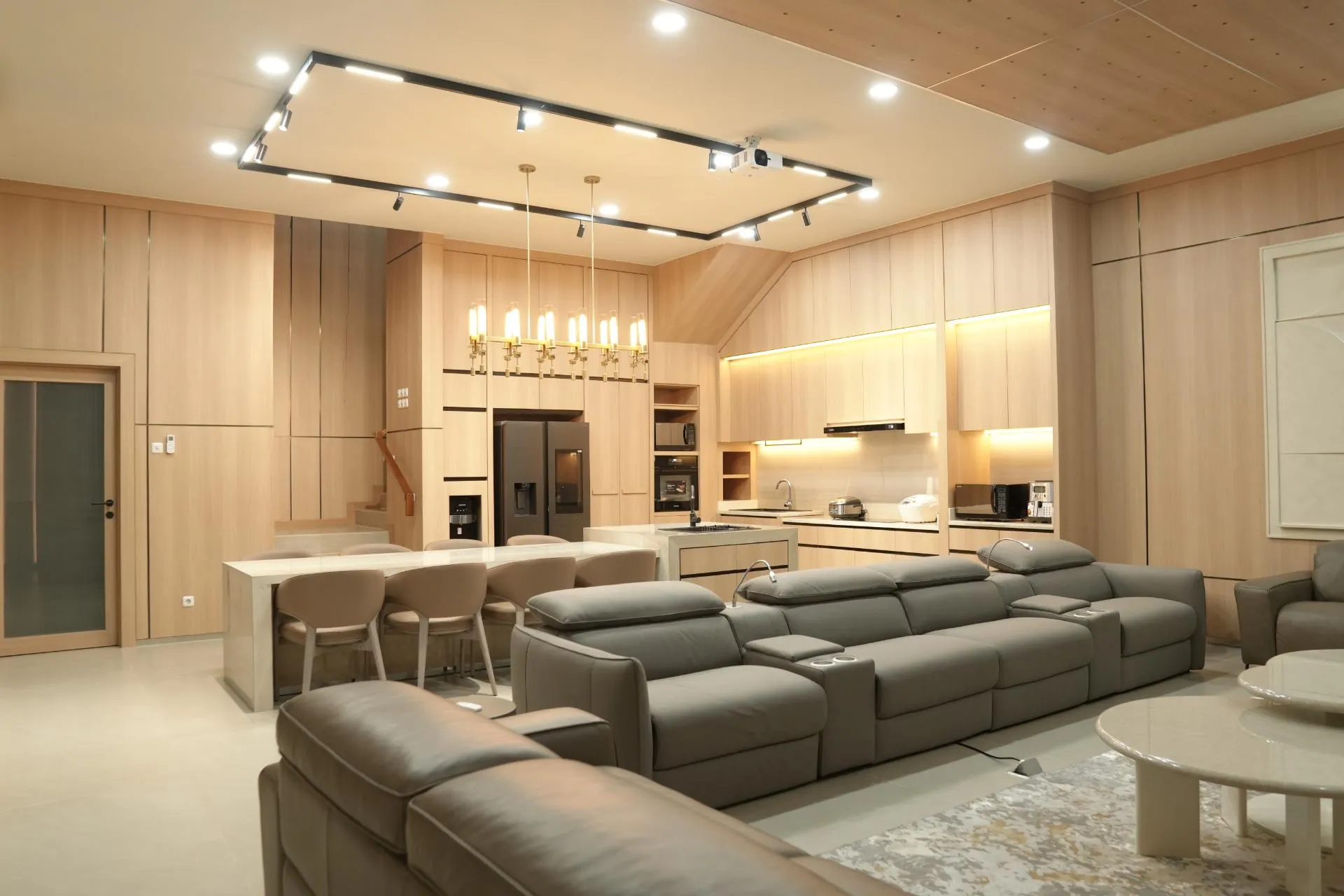 Ruang keluarga menyatu dengan dapur, plafon kayu miring dan perabot built-in